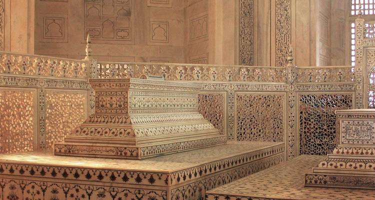 Im Inneren eines Mausoleums befinden sich kunstvoll eingelegte Marmorkenotaphe, die von detaillierten Jali-Gitterwerken umgeben sind.
