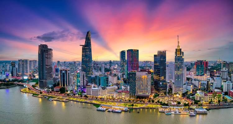 Der moderne Himmel von Ho-Chi-Minh-Stadt leuchtet bei Sonnenuntergang mit lebhaften Strahlen, die sich über dem Saigon-Fluss ausbreiten.