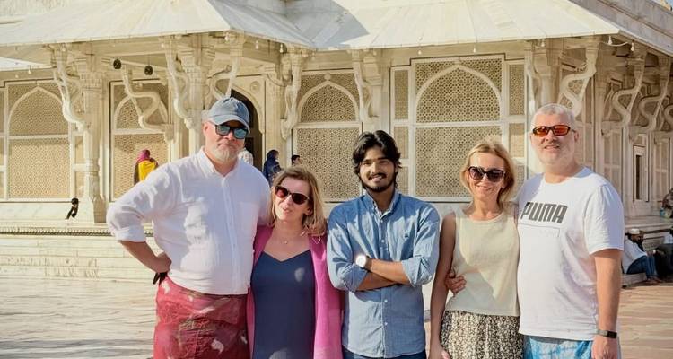 Un pequeño grupo de turistas posa felizmente frente al santuario de mármol blanco en Fatehpur Sikri.