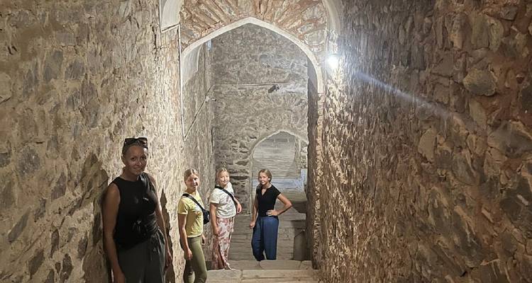 Los visitantes descienden por una escalera de piedra estrecha dentro de las murallas de un fuerte antiguo.