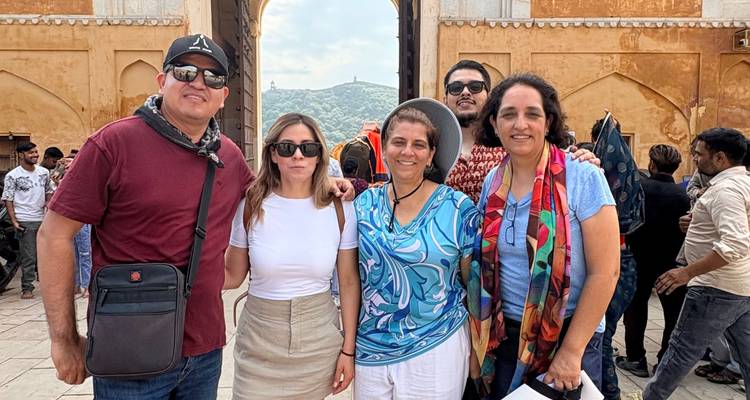 Vijf reizigers die lachen voor de poort van Amber Fort met op afstand gelegen heuvels die omlijst worden door de boogpoort
