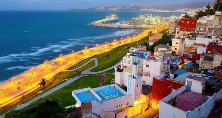 Verhoogd twilight uitzicht op Tangiers kustlijn, verlichte zeepromenade en kleurrijke heuvelbebouwing naast de Atlantische Oceaan.