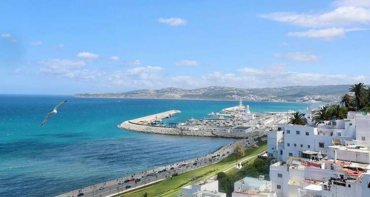 Helder daglicht panorama van Tangiers turkooizen baai, jachthaven en kustweg onder een heldere hemel.