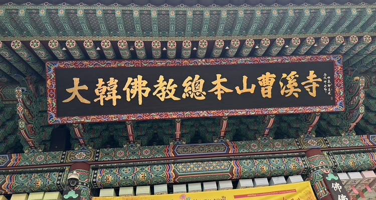 Primer plano de un ornado letrero de templo coreano con aleros pintados de colores vibrantes.