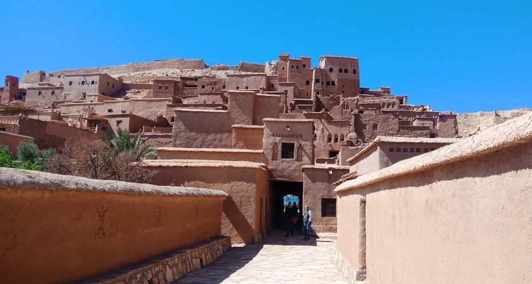 Las paredes de color arcilla te llevan hacia el antiguo ksar fortificado de Ait Benhaddou bajo un cielo azul intenso