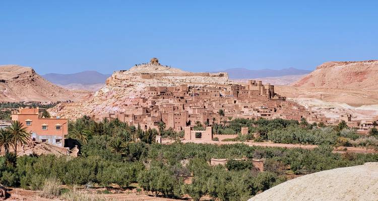 Vista panorámica del ksar de tierra de Ait Benhaddou rodeado de palmeras y colinas áridas