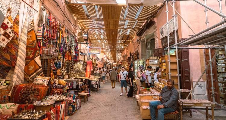 Pasillo del zoco lleno de color repleto de textiles, cerámica y compradores en Marrakech
