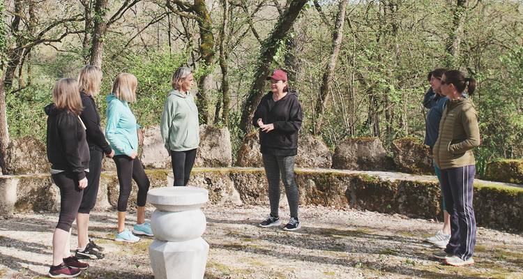 Small group of women listening to a guide in a forest clearing during a wellness retreat.