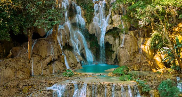 Der mehrstufige Kuang Si Wasserfall, der in ein türkises Becken fällt und von üppigem Regenwald umgeben ist.