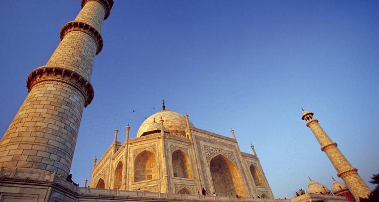 Angle de prise de vue dramatiquement ascendant du mausolée en marbre du Taj Mahal et de ses minarets sur un ciel crépusculaire d'un bleu profond.