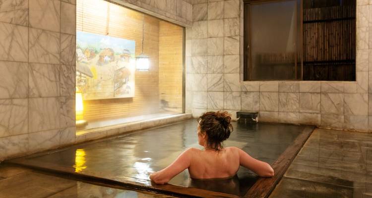 Vrouw ontspant alleen in een dampend binnenbad met marmer onsen.