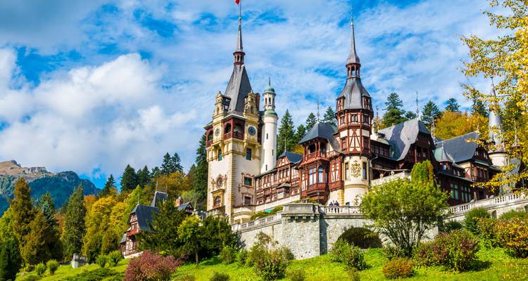 Fairytale spires and timbered facades of Peleș Castle surrounded by alpine forest.