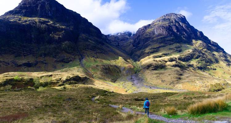 Un randonnéur solitaire marche à travers la vallée spectaculaire de Glencoe, sous des pics imposants.
