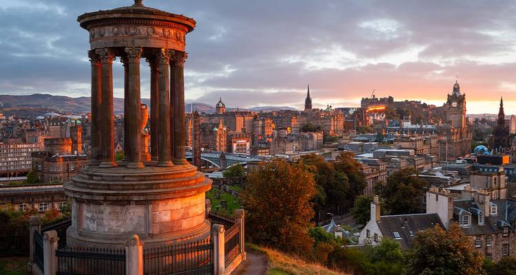 Vue du coucher de soleil depuis la colline de Calton avec le Monument Dugald Stewart et la ligne d'horizon d'Édimbourg avec le château illuminé par une lumière chaude.
