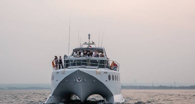 Luxe witte jacht dat bij zonsopgang vaart met passagiers die op het voordek zijn verzameld.