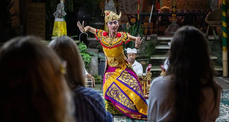 Balinese danser in kleurrijke kostuum die optreedt voor een intiem publiek in traditioneel paviljoen.