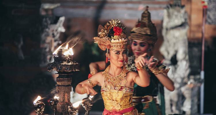 Twee Balinese dansers die 's avonds met fakkels optreden in een traditionele tempelplein.