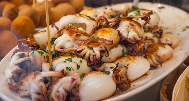 Plateau de fruits de mer avec des petits calamars cuits garnis de persil dans un établissement local.