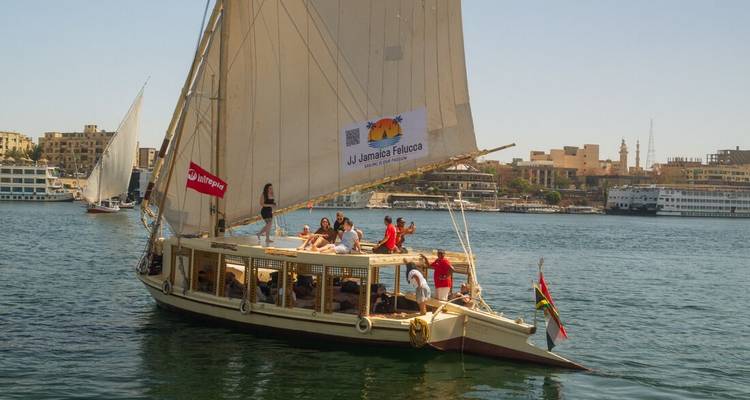 Felucca with travellers sails on the Nile River on a sunny day