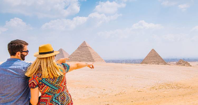 Couple points toward pyramid panorama under bright blue sky