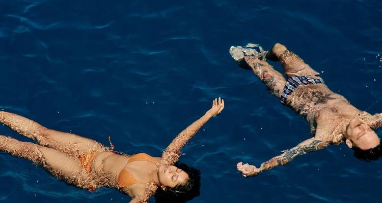 Overhead shot of a man and woman calmly floating on deep blue sea water