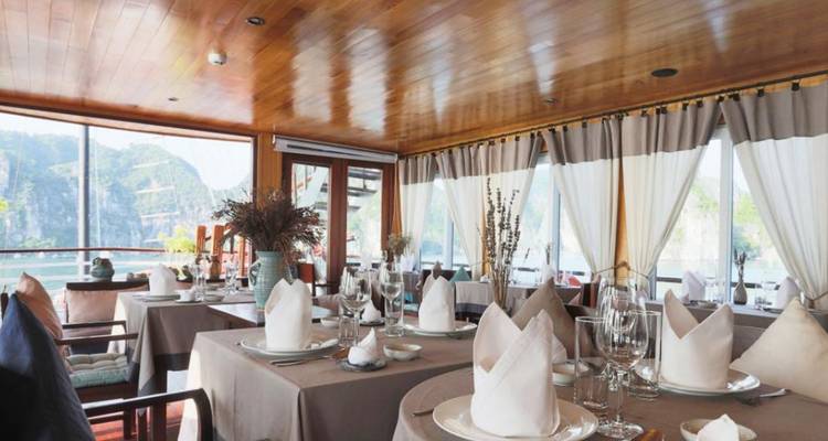 Salle à manger élégante à bord d'un navire de croisière avec de grandes fenêtres donnant sur des paysages karstiques