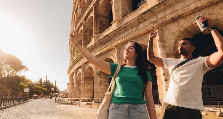 Deux voyageurs célèbrent avec un selfie et le poing levé à côté de l'emblématique Colosseum de Rome.