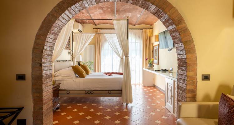 Chambre boutique élégante avec lit à quatre colonnes, sols en terre cuite et lumière naturelle douce à travers des rideaux voilés.