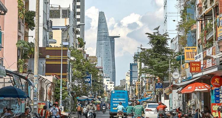Rue de la ville animée remplie de motos et de magasins avec la tour financière Bitexco s'élevant en arrière-plan