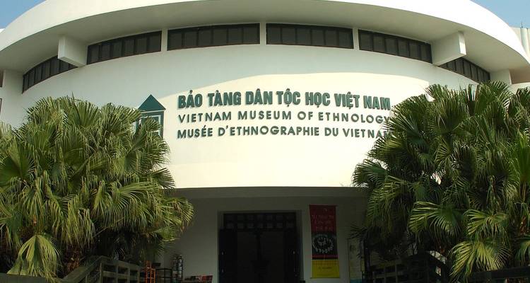 Entrance of Vietnam Museum of Ethnology with bilingual signage and palm trees in front.