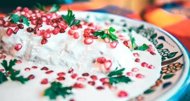 Traditional Mexican chile en nogada covered in creamy walnut sauce and garnished with pomegranate seeds.
