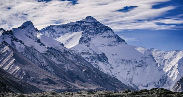 Gros plan dramatique de la face nord enneigée du Mont Everest sous des nuages d'altitude striés.