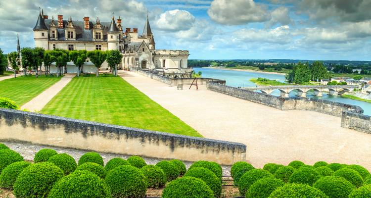 Elegant kasteel in de Loire-vallei met verzorgde gazons en uitzicht op de rivier onder dramatische wolken.