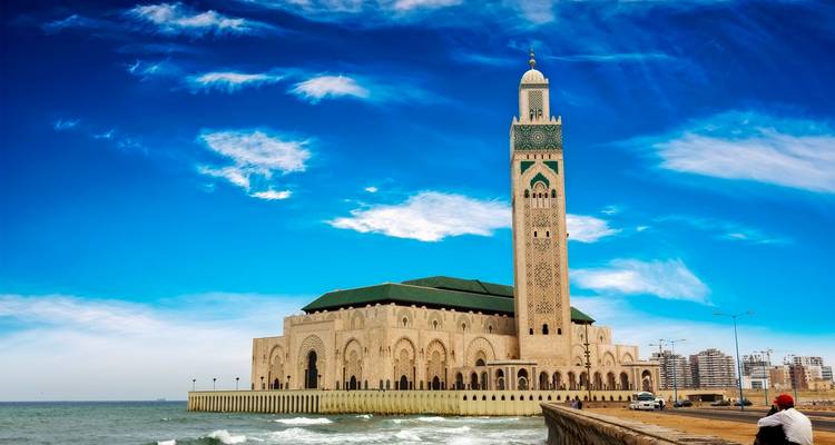 Hassan II Mosque in Casablanca standing beside the Atlantic with blue sky and waves.