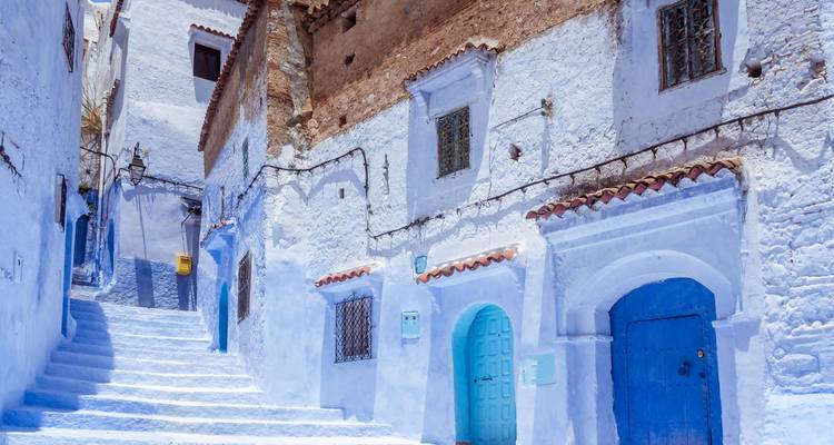 Narrow uphill alley of white and blue painted houses with colorful doors in Chefchaouen