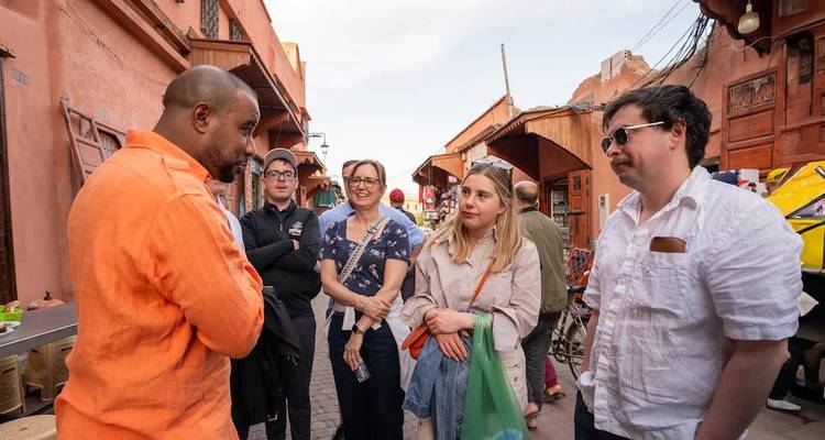 Gids die reizigers begeleidt in een smal roze steegje van de medina van Marrakesh