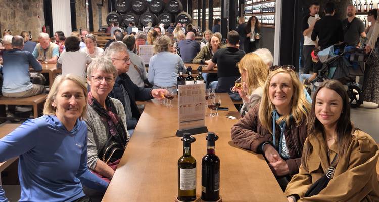 Salle de dégustation de vin intérieure animée avec des personnes assises à de longues tables en bois