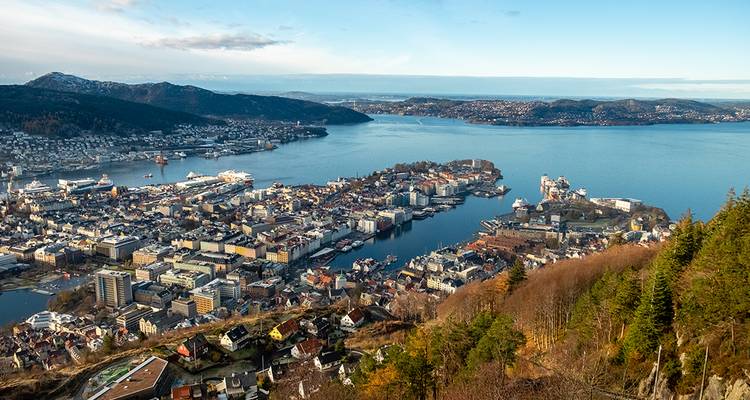 Breed luchtfoto van de skyline van Bergen, de haven en omliggende fjorden op een heldere dag.