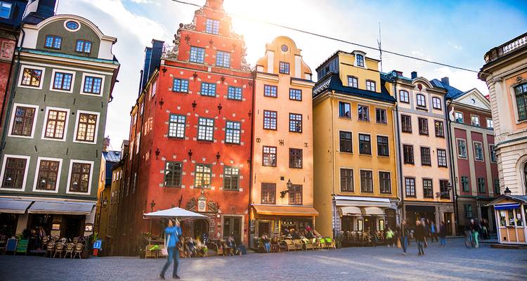 De felgekleurde historische gebouwen van Stockholms Gamla Stan gloeien in de zon terwijl voorbijgangers wazig over het plein lopen.