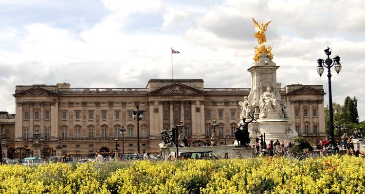 Le Palais de Buckingham derrière des parterres de fleurs d'un jaune vibrant avec le Mémorial de Victoria bien en évidence à l'avant.