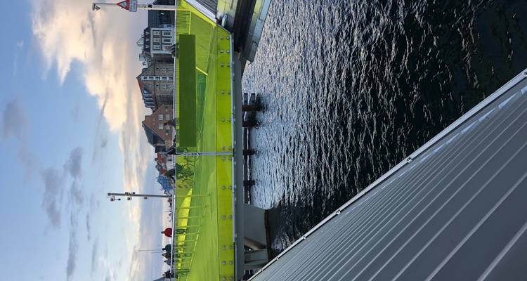 Un pont pour piétons et vélos d'un vert citron éclatant enjambe un canal de Copenhague sous un ciel de soirée aux teintes pastel.