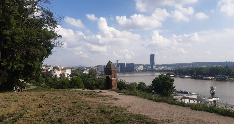 Mirador en parque con césped que da vista al Río Sava y al horizonte de Belgrado con una torre de ladrillo solitaria.