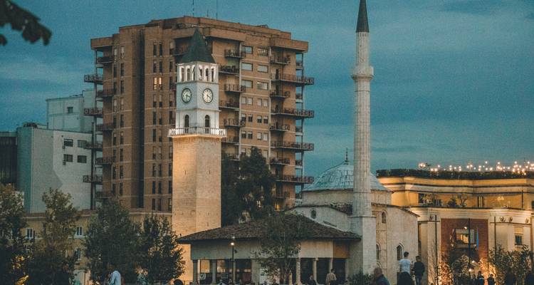 Avondscène van Tirana's klokkentoren en moskee verlicht tegen een schemering blauwe lucht