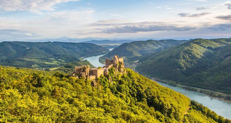Adembenemend luchtfoto van de verwoeste burcht Aggstein die boven de kronkelende Donau uittorent, omgeven door weelderige groene heuvels.