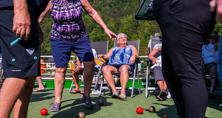 Kreuzfahrtpassagiere spielen Boccia auf dem Sonnendeck mit bewaldeten Hügeln im Hintergrund