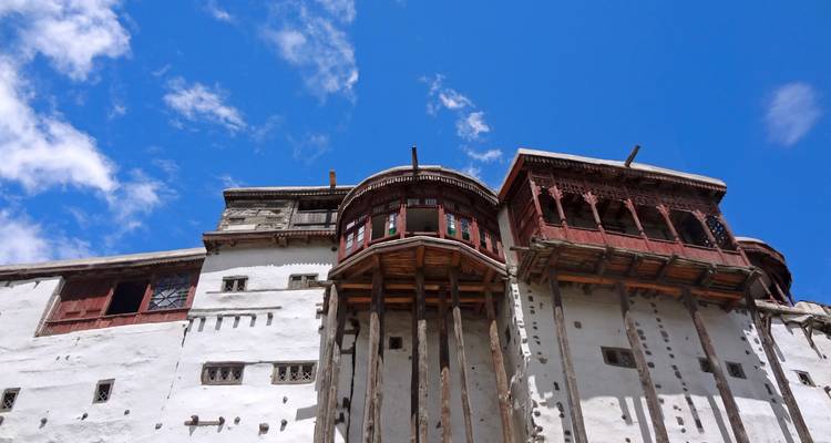 La fachada de madera blanca y roja del histórico Fuerte Baltit se eleva contra un cielo azul brillante de gran altitud.