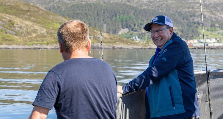 Deux hommes discutant et pechant à partir d'un petit bateau sur les eaux calmes d'un fjord nordique