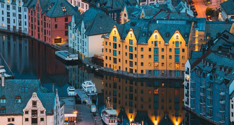 Vue en fin d'après-midi des bâtiments colorés de style Art Nouveau se reflétant dans le port d'Ålesund