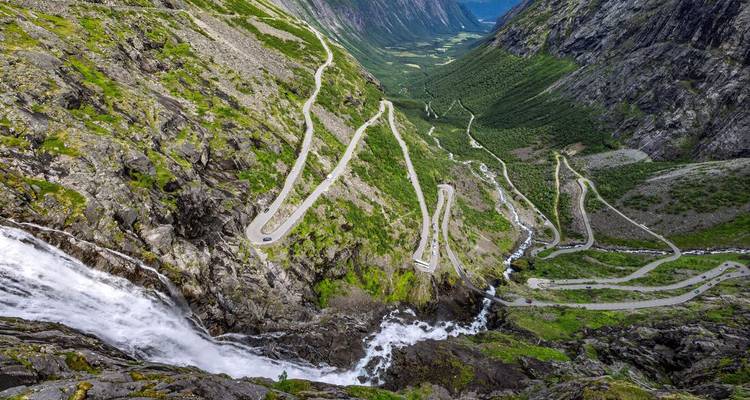 Les virages en épingle à cheveux du col de montagne de Trollstigen descendant à côté d'une cascade.