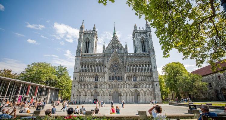 Façade gothique de la cathédrale de Nidaros avec des personnes se détendant sur la place ensoleillée
